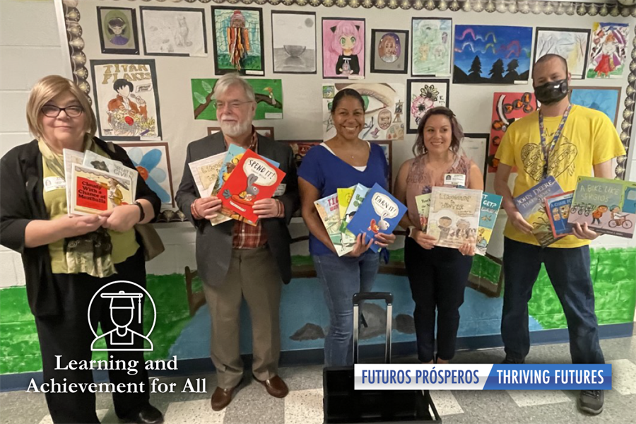 Learning and achievement for all. Futuros prosperos. Launching thriving futures. Photo of school administrators and organization representatives with donated books
