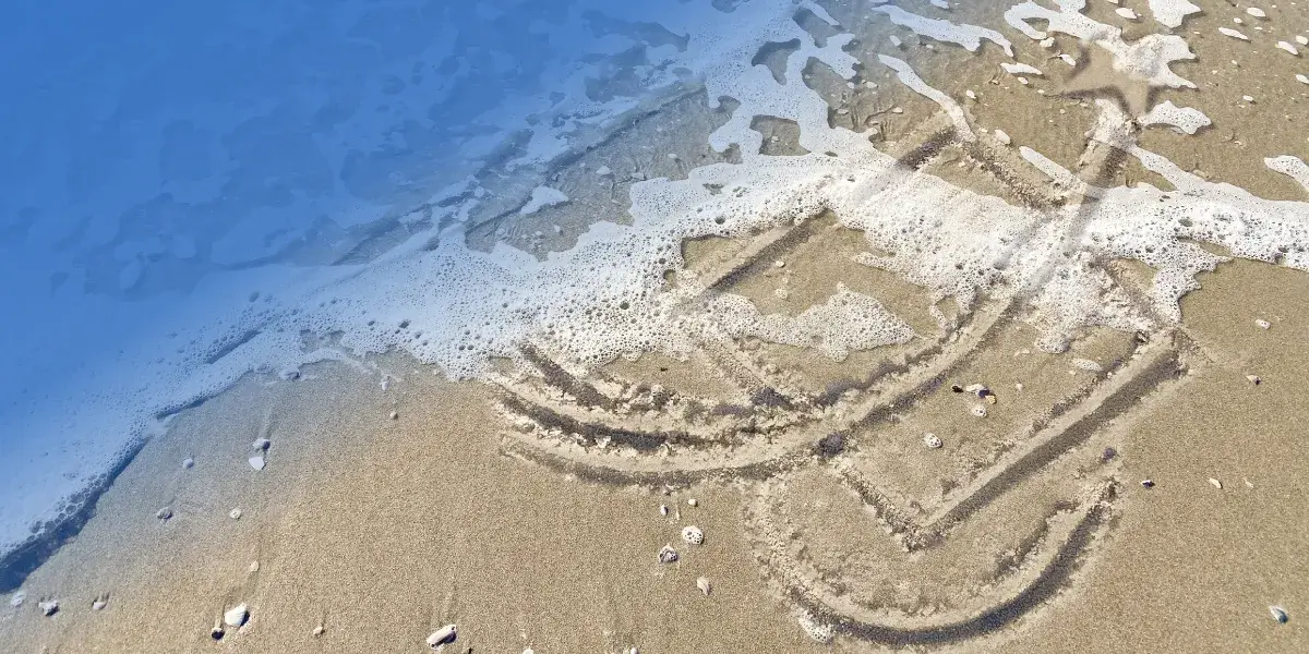 PWCS logo drawn in sand on a beach