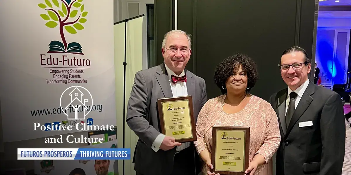 Three smiling and formally dressed ndividuals standing grouped together to the right of a sign with the Edu-Futuro organization logo. Two of the people, William Bixby, PWCS associate superintendent for high schools, and Chevelli Smith, principal of Freedom High School, are holding award plaques