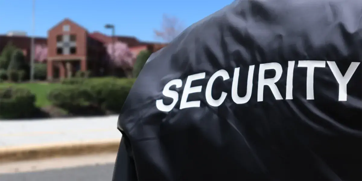 School Security Officer wearing a jacket that says "security" standing in front of a school