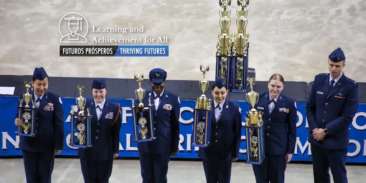 Six students in military uniforms, each holding a trophy and lined up in front of a banner at the U.S. Air Force Junior Reserve Officer Training Corps (AFJROTC) Open Drill Nationals championship 