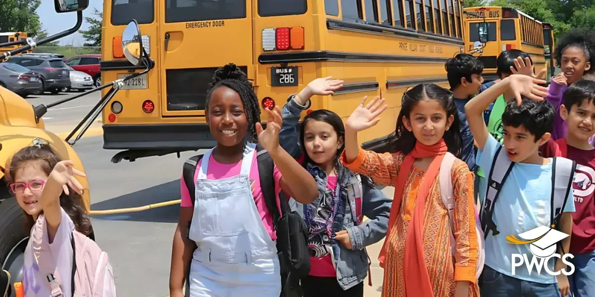 Group of students waving to the camera while they get on the bus