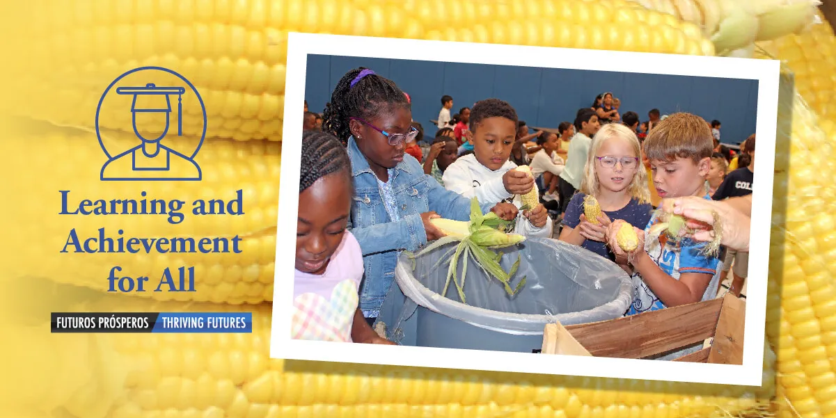 Second grade students shucking corn in cafeteria