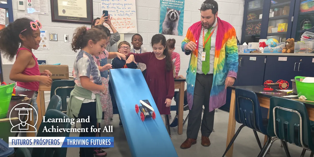 Photo of students gathered around a trial run of their engineered cart