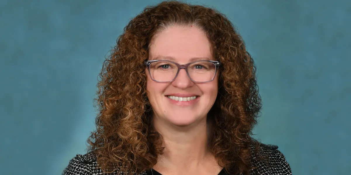 Smiling head and shoulder photo of school board member, Lisa Zargarpur wearing glasses and with long, curly hair
