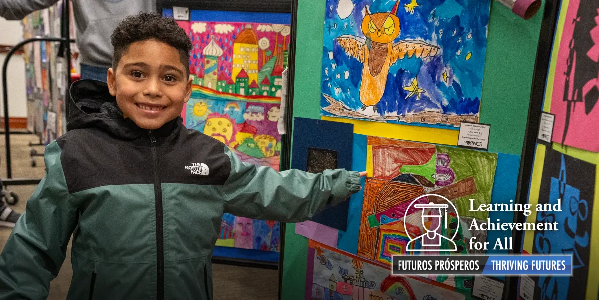 A young student pointing at his artwork