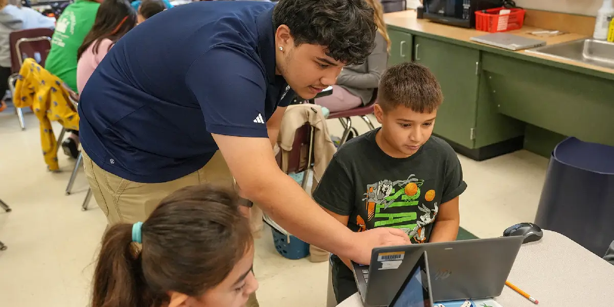 Technical Supper Specialist assisting a student with their computer in an elementary school classroom