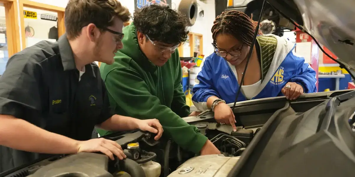 Three students in the automotive technology program at Osbourn Park High School working on a car