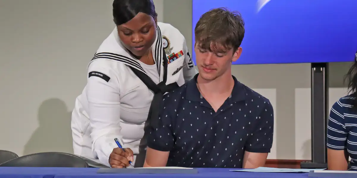 A PWCS high school senior and a U.S. Navy recruiter sign a commitment form at the 2024 Career and Technical Education Signing Day