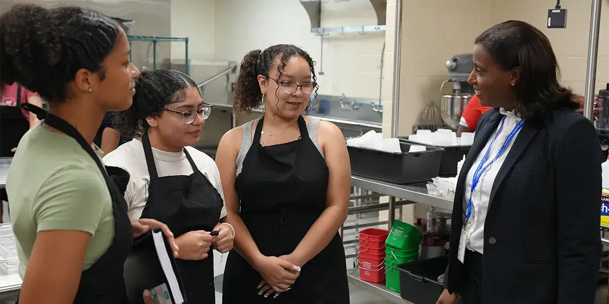 Superintendent LaTanya D. McDade talking with three culinary arts students at Gar-Field High School