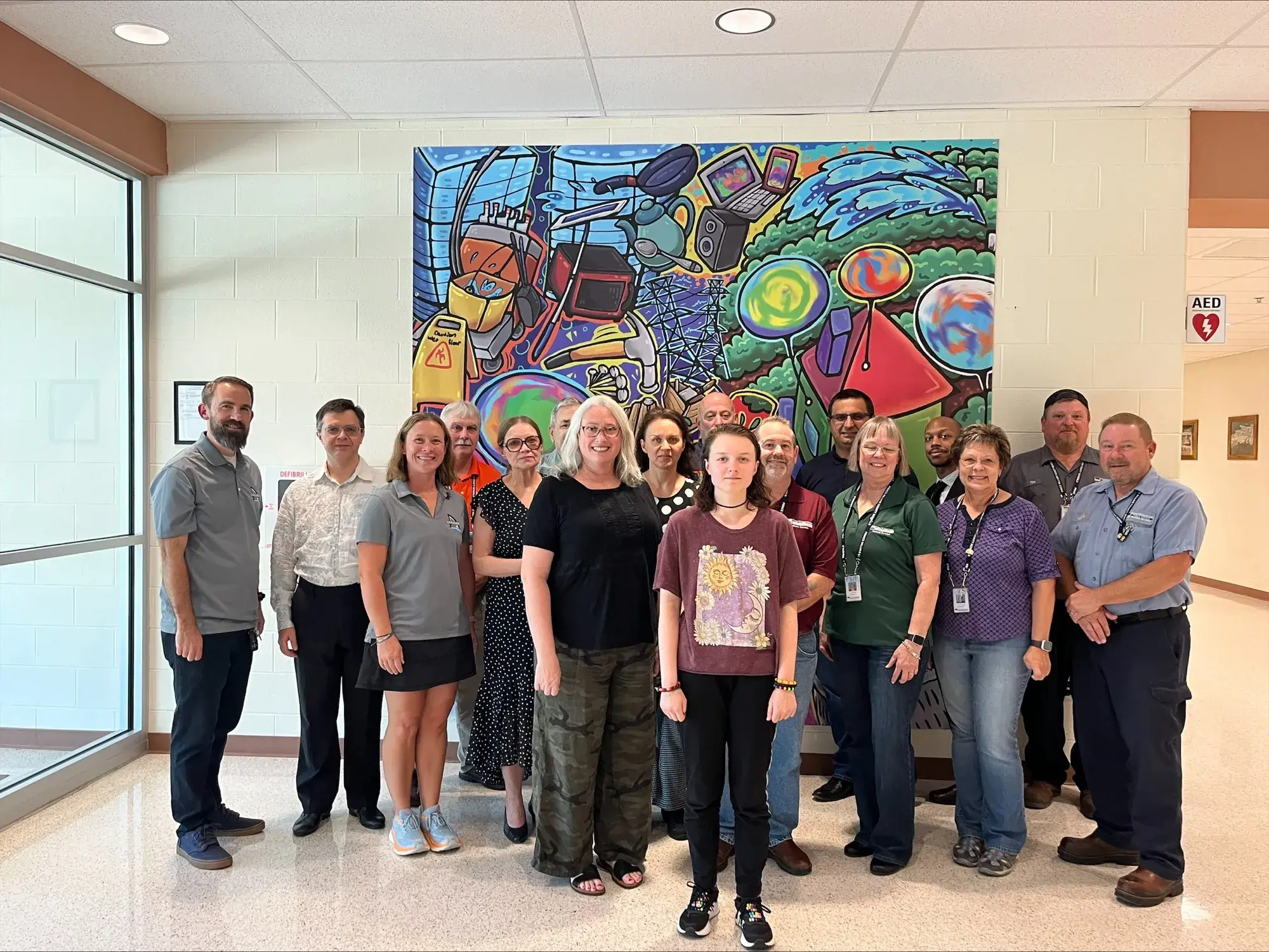 Facilities Department staff posing in front of the mural