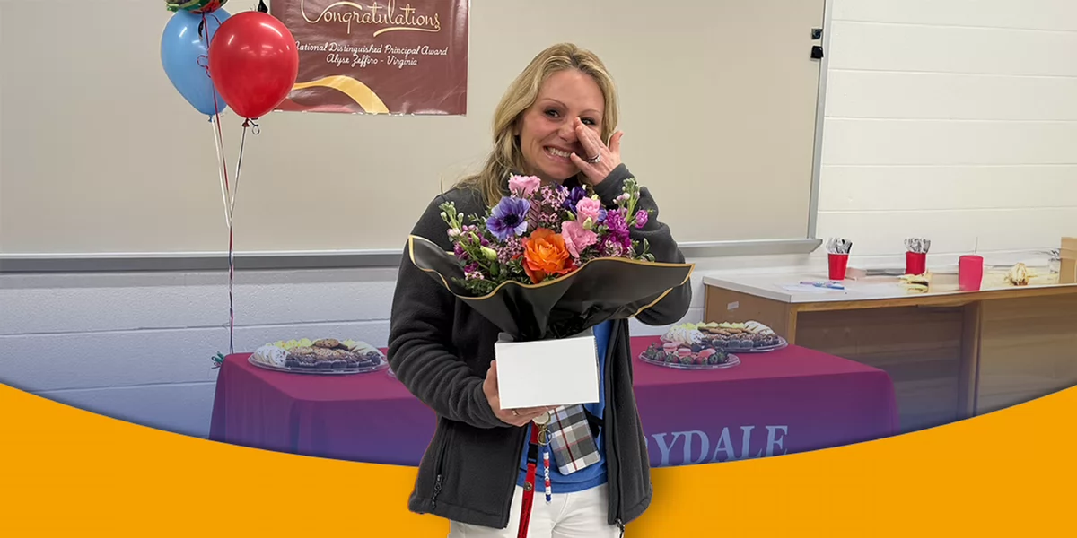 A smiling woman holds a bouquet of colorful flowers in front of a decorated table with snacks and balloons, celebrating a special achievement.