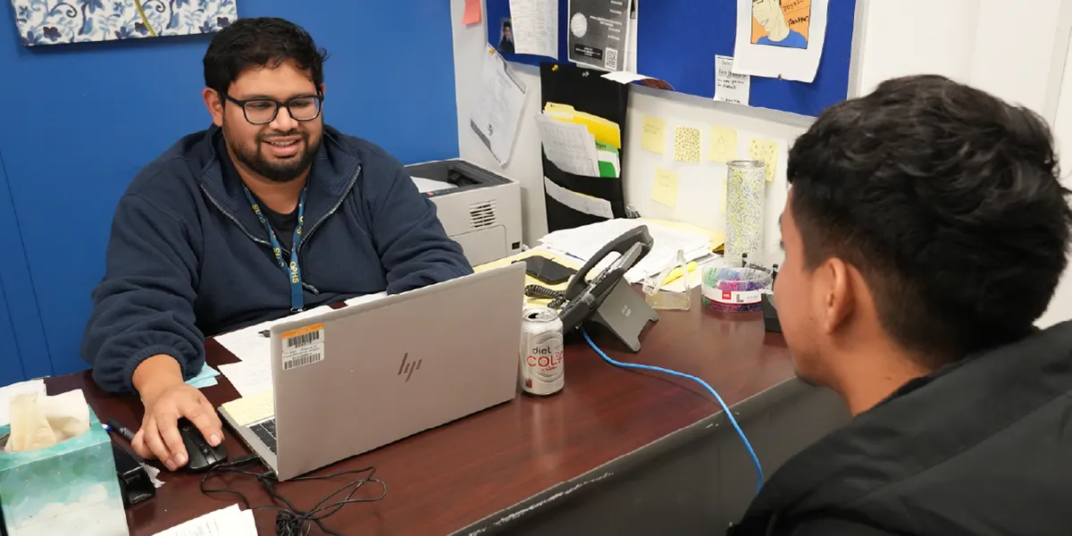 School counselor at Osbourn Park High School sitting at a desk while speaking with a student