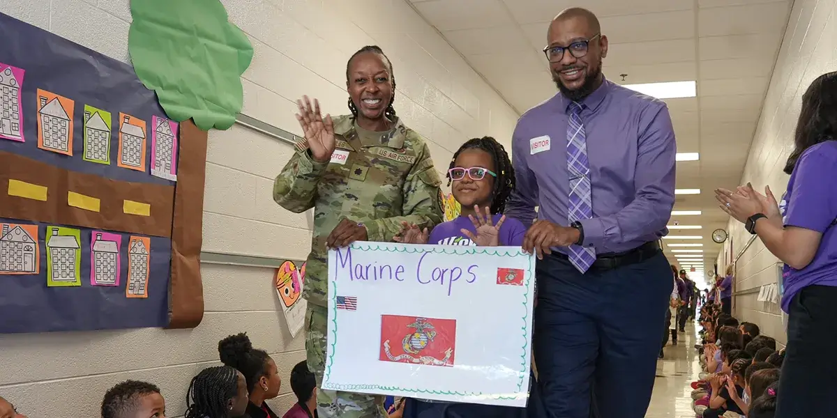 A Marine Corps military family walking through halls of Porter Traditional School during the celebration of Purple Up! Day