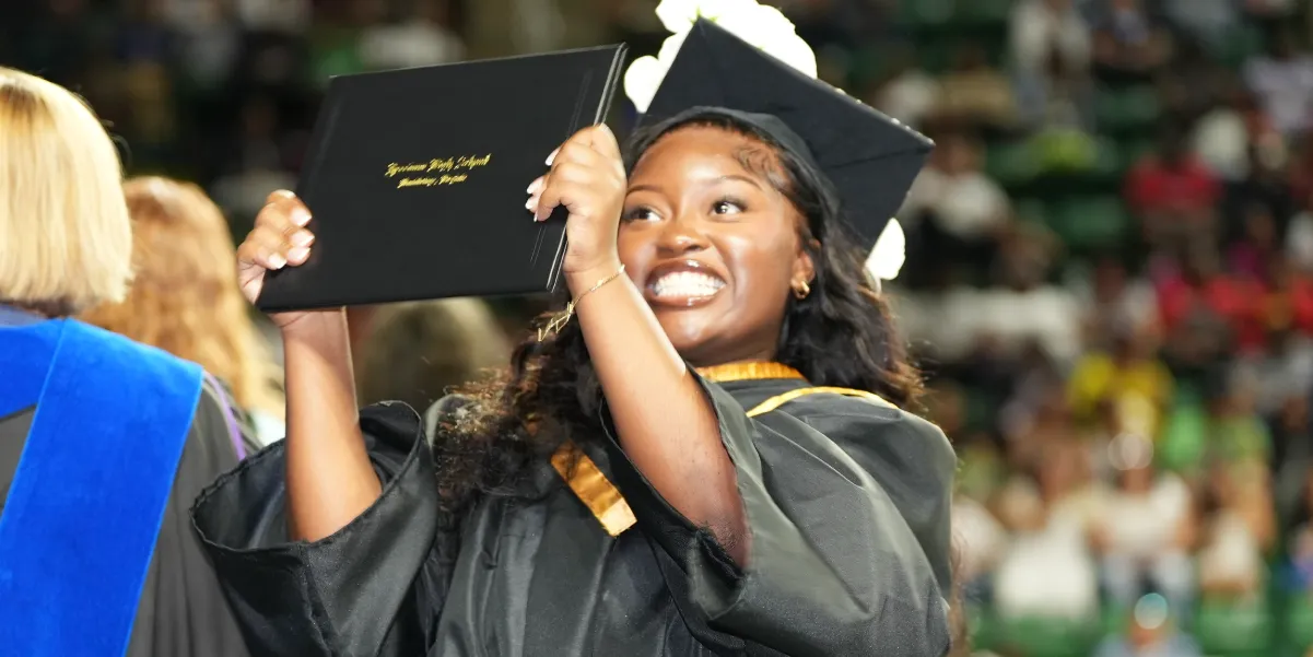 2024 Freedom High School graduate holding up her diploma shortly after receiving it