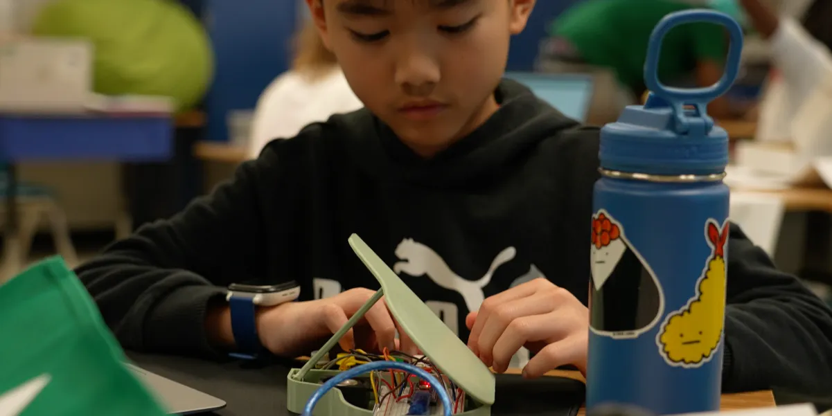 Student sitting at a table working with a circuit board during a summer program in 2024