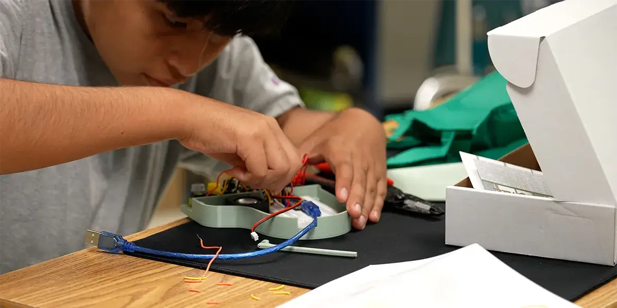 Student working on a circuit board during a Discovery enrichment summer camp