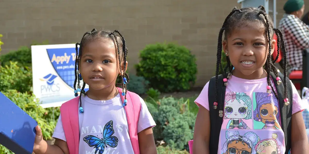 Two elementary school students standing in front of their on the first day of school