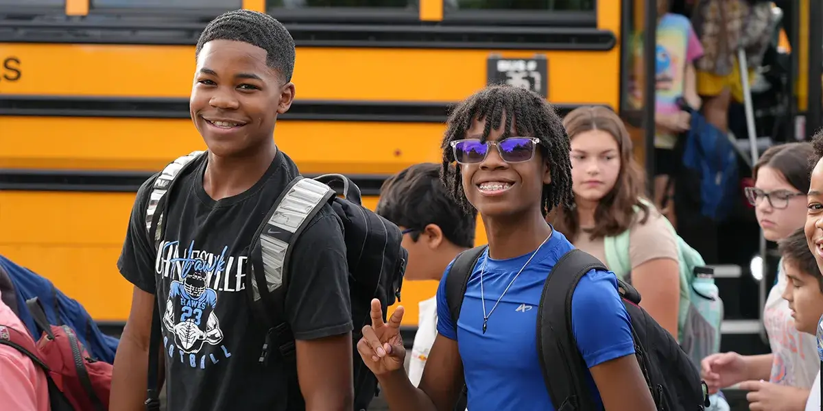 A Gainesville Middle School student holds up a peace sign while students enter the building on the first day of school