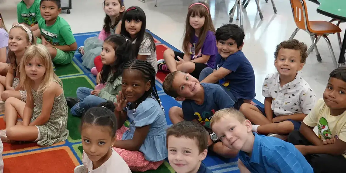Elementary school students seated on a carpet in a classroom
