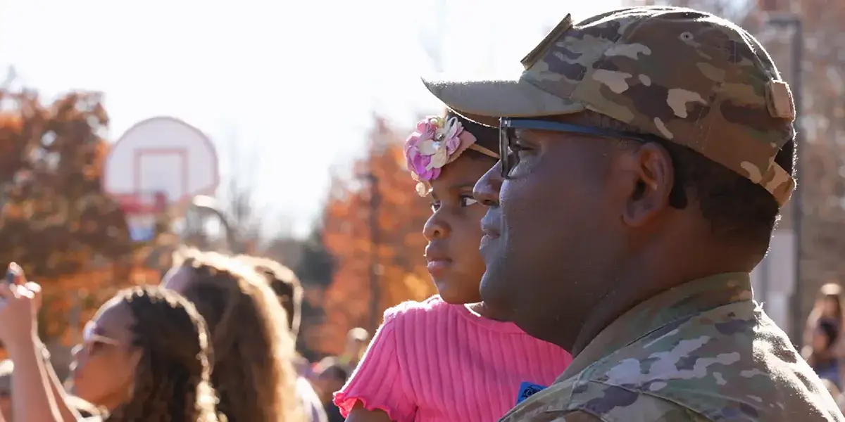 A member of the military holds their child at a PWCS event