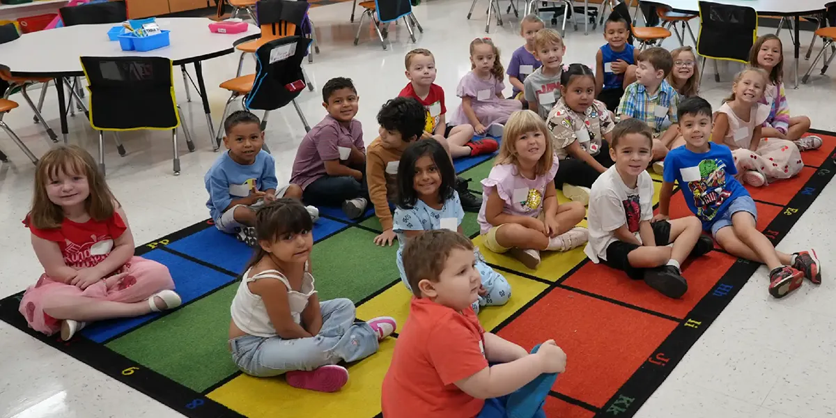 Kindergarten students sitting on the floor in a classroom