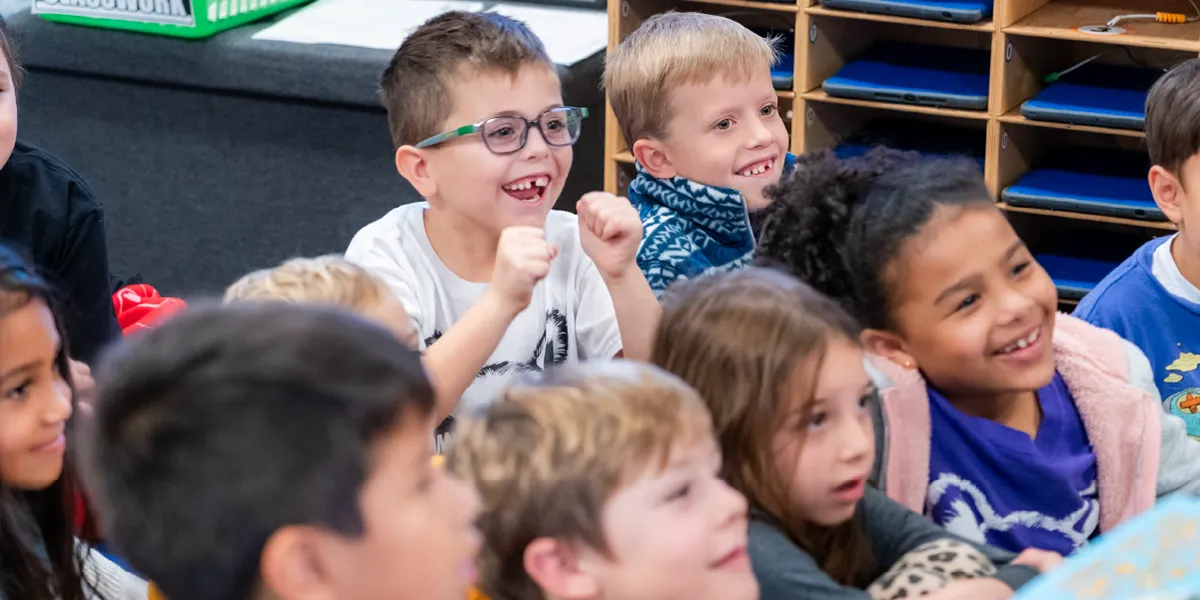 Smiling elementary school students seated on the floor during class