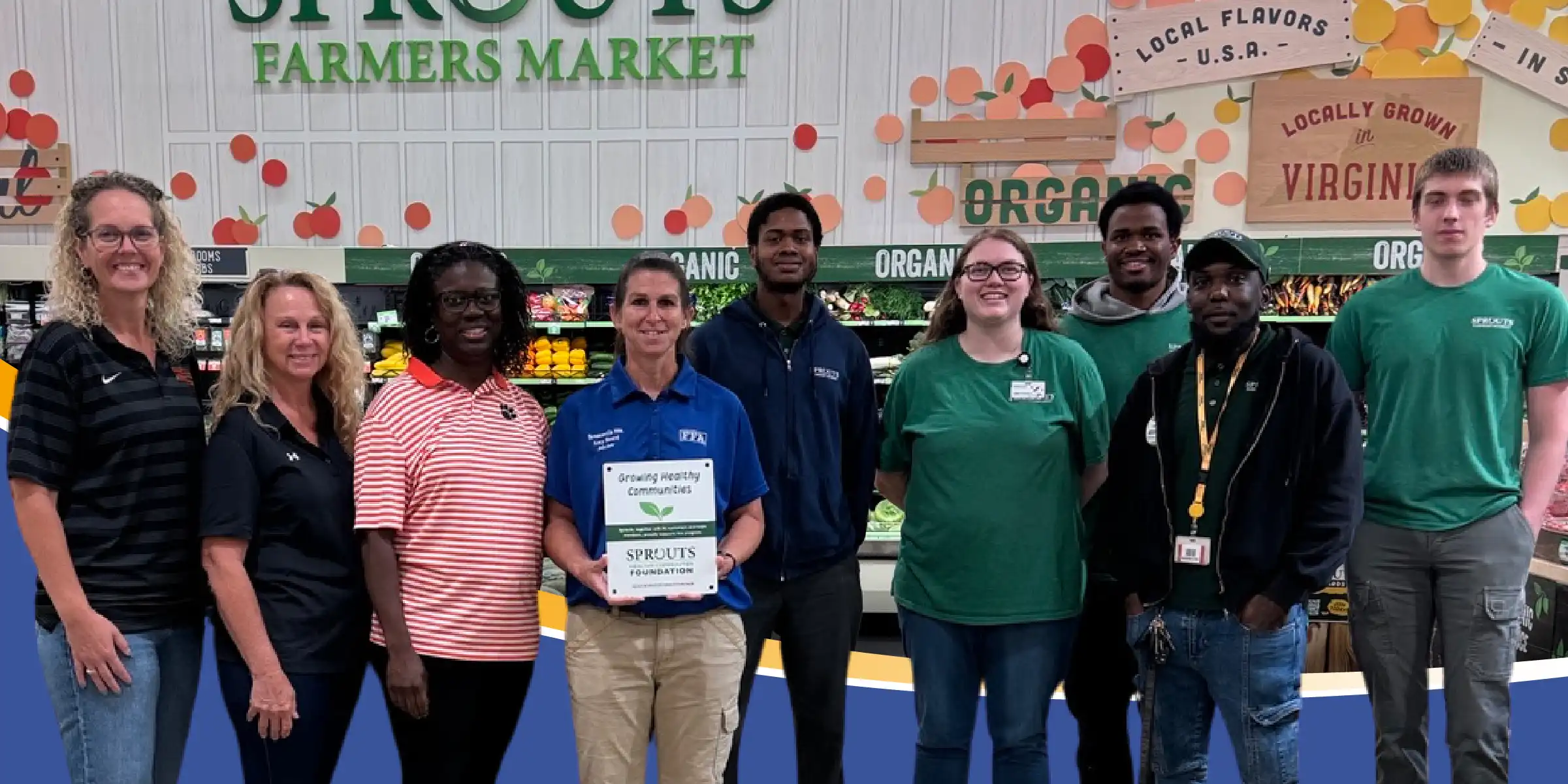 Store staff and Brentsville representatives pose together in the produce department at Sprouts Farmers Market, with one team member holding a Sprouts Foundation “Growing Healthy Communities” award plaque.