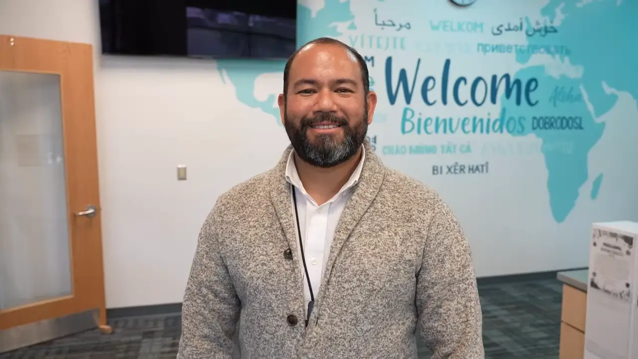 parent liaison standing in front of a school mural