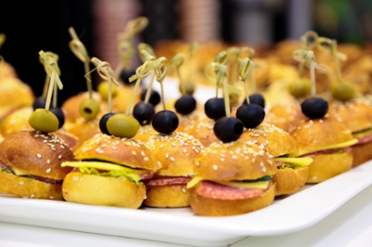 A catered platter of food consisting of mini hamburgers (sliders)