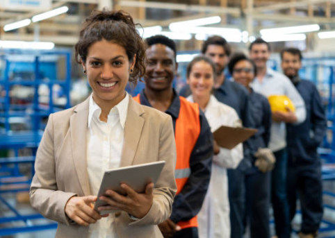 Workers of various occupations standing in a line with a woman holding a clipboard in the front