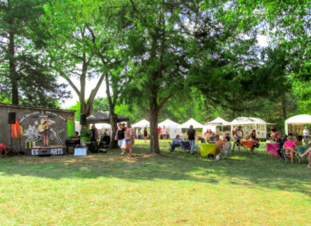 An outdoor vendor fair setup on a grass field