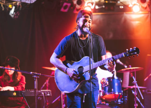 a musician on stage playing a guitar and singing. woman in background playing keyboard on stage a musician on stage playing a guitar and singing. woman in background playing keyboard on stage