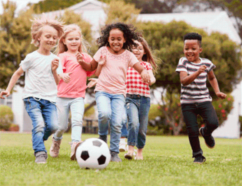 Group of five children playing soccer on a grass
