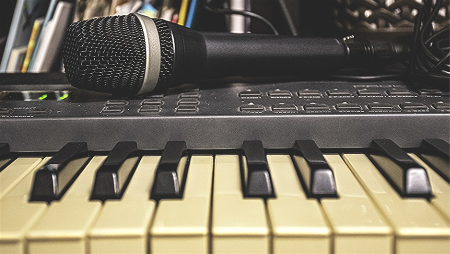 A keyboard with a microphone resting on it A keyboard with a microphone resting on it