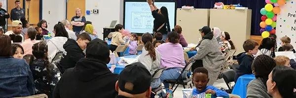 Families seated at tables at the beginning for a family engagement event