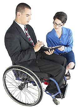 Man sitting in a wheelchair with a woman crouching next to him