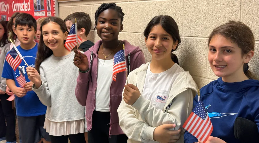 students standing in hallway holding American flags