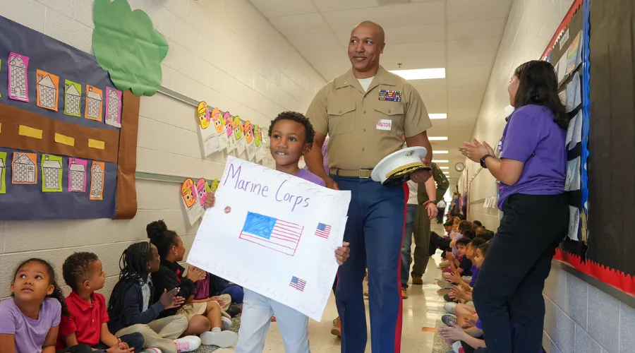 father in marine uniform and young son walking through school hallway