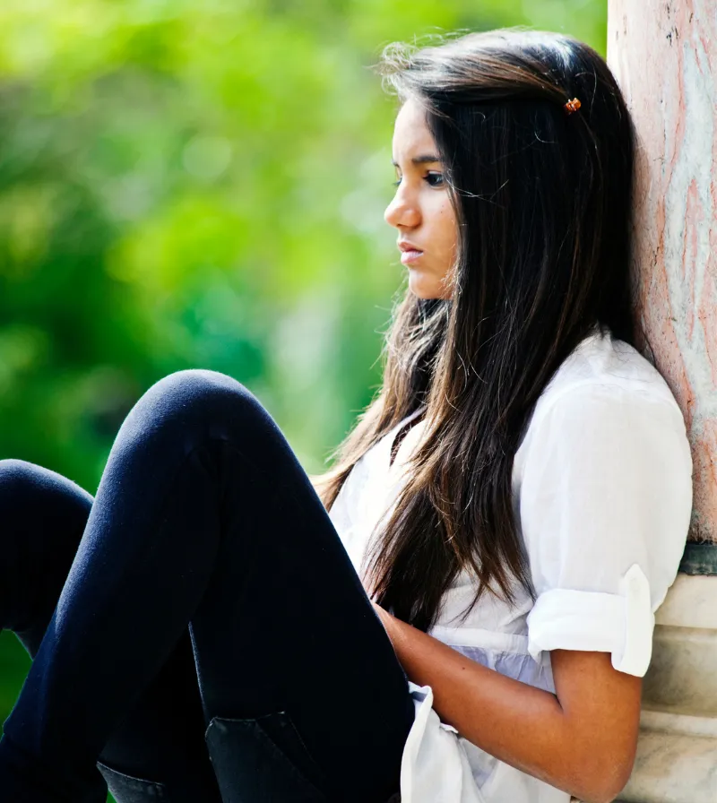 photo of a girl sitting and leaning against wall