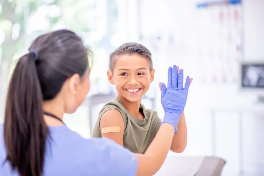 Nurse high-fiving a boy after he received a vaccination