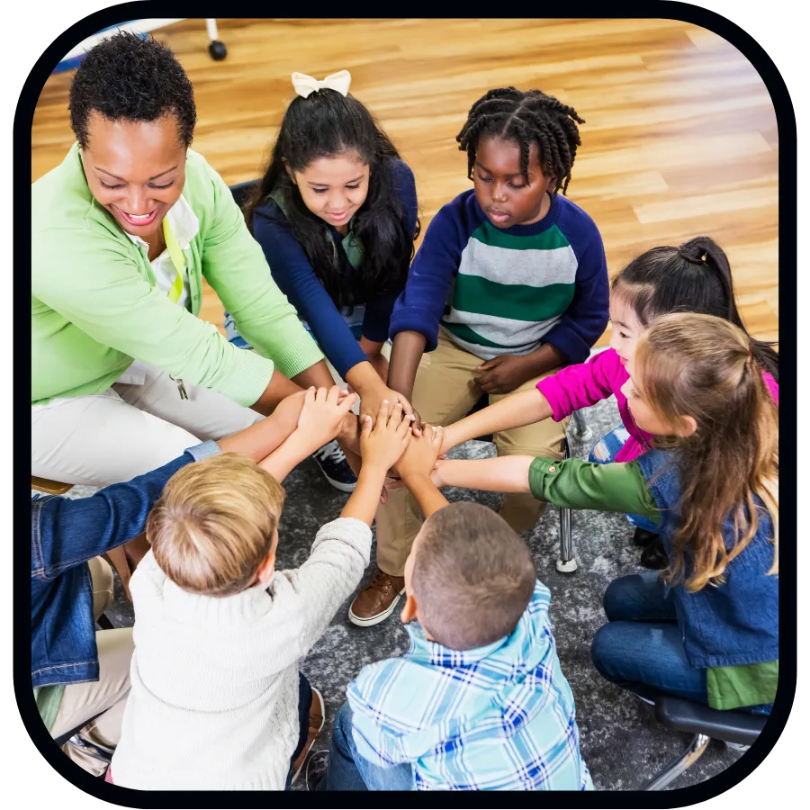 School teacher and six young children with hands outstretched touching in the middle